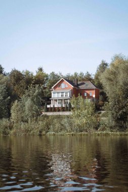 Nehir kenarındaki ev. Nehir kenarındaki bir binanın yaz fotoğrafı.