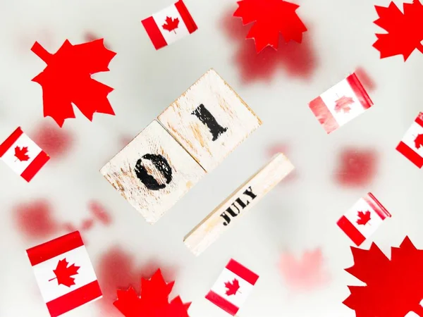 July 1, Happy Canada Day. Red maple leaves, flags and a wooden calendar on a transparent foggy background. The concept of freedom and patriotism, independence and victory. High quality photo
