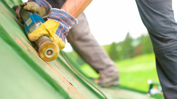 Mann arbeitet auf dem Dach und schleift Farbe — Stockfoto