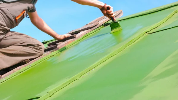 刷绿漆的屋顶上的人 — 图库照片