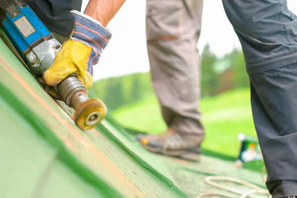 Man aan het werk op het dak, Sandering verf Stockfoto