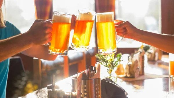 Clinking con amigos usando vidrio de cerveza Imagen de stock