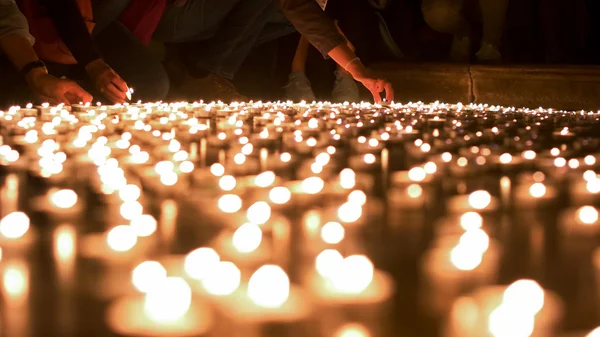 Gente encendiendo y colocando velas a otros Imagen de archivo