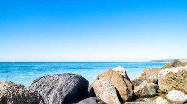 Vada sahilindeki taşlar, şeffaf, turkuaz su ve beyaz kum. Seyahat ve doğa kavramı.