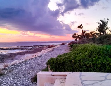 Akdeniz üzerinde gün batımı. Kıbrıs adasının egzotik sahillerinde palmiye ağaçları.