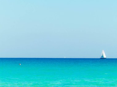 A boat in the turquoise waters of the Mediterranean Sea. Copy space on blue sky. Travel and leisure concept.