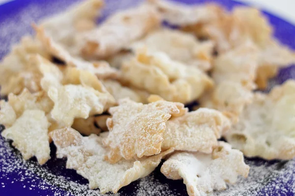 Primo piano dei biscotti di carnevale Chiacchiere (o Bugie) -italiano su piatto blu — Foto Stock