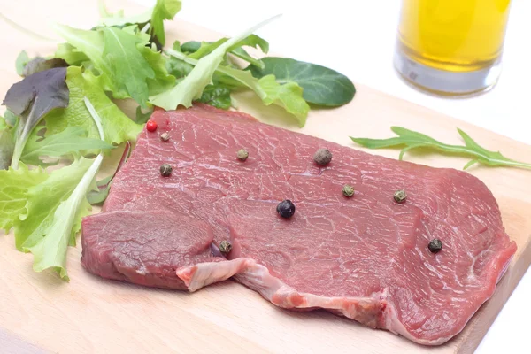 Rohes Steak auf Holzschneidebrett mit Salat — Stockfoto