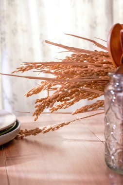 Pencere kenarındaki güneş ışığının altında pirinç kulakları ve buğday kulakları.