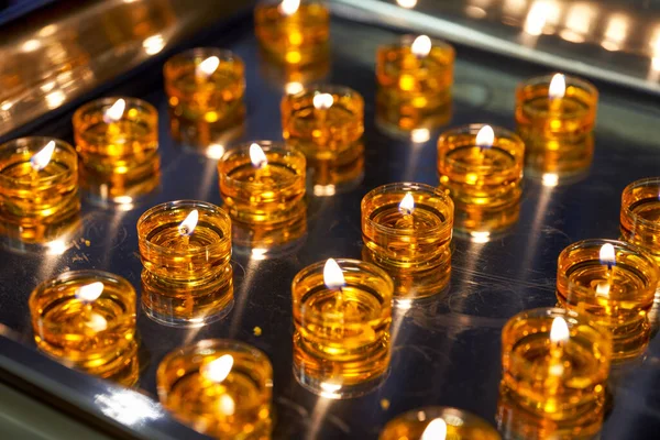 The tray is filled with lighted golden candles