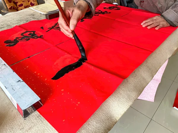 A calligrapher is creating and writing Spring Festival couplets, Chinese New Year Spring Festival. Translation: Spring is in many cities.
