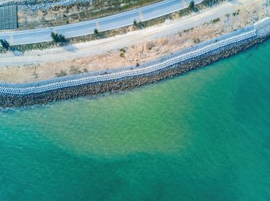 Sahil otobanının çimento bloğu dalgalanması, deniz kenarının havadan çekilmiş fotoğrafı.