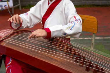 Küçük bir kız guzheng enstrümanı çalıyor.