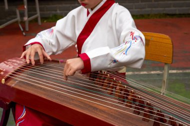 Küçük bir kız guzheng enstrümanı çalıyor.