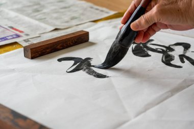 Bir kaligraf, büyük bir fırçayla, fırçaya yakın çekim ile kaligrafi karakterleri yazar. Çevirisi: Yükseklik çok soğuk