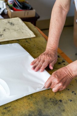 Bir kaligraf pirinç kağıdı katlıyor ve hat hazırlığı yapıyor.