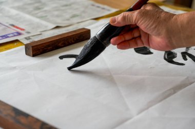 Bir kaligraf, büyük bir fırçayla, fırçaya yakın çekim ile kaligrafi karakterleri yazar. Çevirisi: Yükseklik çok soğuk