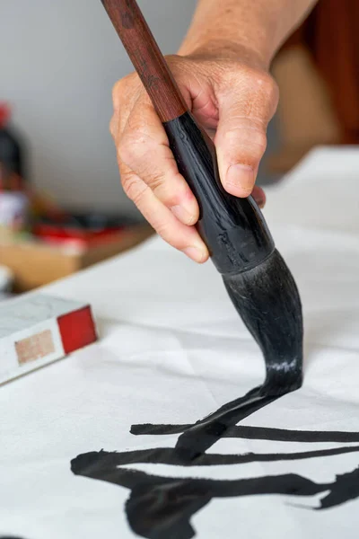 A calligrapher is writing calligraphy characters with a large brush, a close-up of the brush. Translation: The heights are too cold