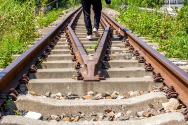 Eski paslı tren raylarında yürüyen bir adam