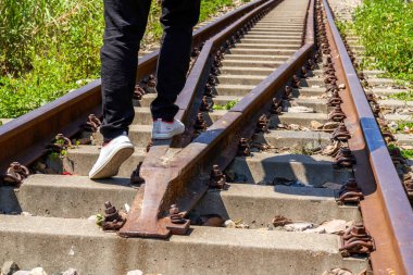 Eski paslı tren raylarında yürüyen bir adam