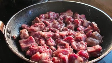 Bir şef kızartma tavasında domuz pirzolası pişiriyor.