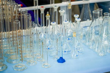 Masanın üzerinde cam kimyasal enstrümanlar ve konteynırlar var.