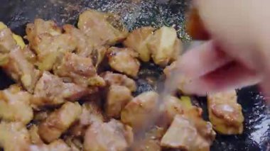 Kızarmış domuz pirzolası pişiren şefin yakın çekimi.