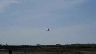 Bir ticari uçak yaklaşıyor ve havaalanı pistine iniyor..