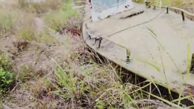 Vahşi doğada terk edilmiş, harap olmuş, paslı bir devriye botu..