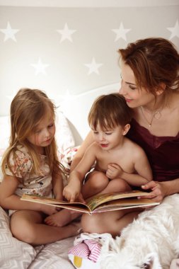 Annem yatakta küçük bir kız ve oğlana masal okuyor.