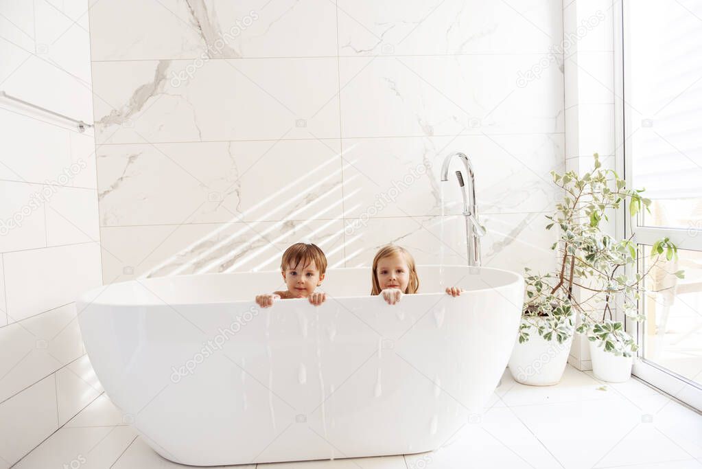 Little brother and sister having fun and taking a bubble bath