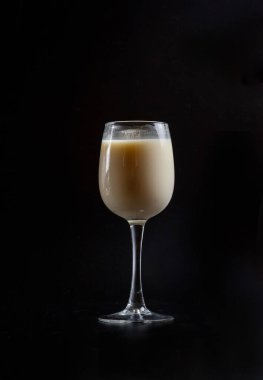 Siyah arka planda bir bardakta süt