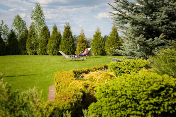 Menina descansando em uma espreguiçadeira no jardim — Fotografia de Stock