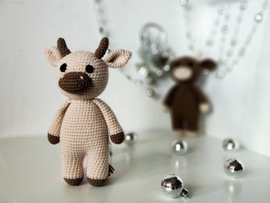 Beyaz arka planda bir çift boğa ve Noel süslemeleri. Tığ işi yumuşak oyuncaklar, el yapımı. 2021
