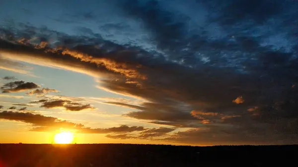 Hermosa puesta de sol sobre el campo y el bosque. El sol se refleja en las nubes. Vista desde arriba. Ural Rusia 2021. — Foto de Stock