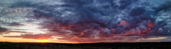 Hermosa puesta de sol sobre el campo y el bosque. El sol se refleja en las nubes. Vista desde arriba. Ural Rusia 2021. — Foto de Stock