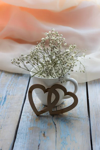 Cam vazoda bir buket beyaz çiçek ya da açık romantik arka planda bir fincan.
