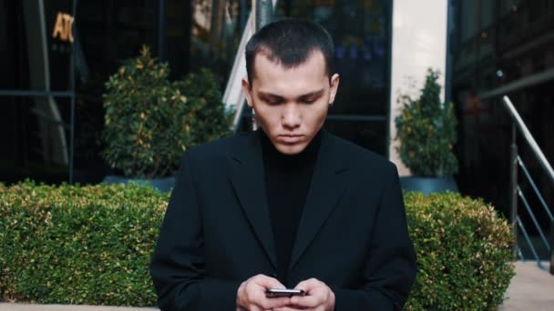 Gravi uomini d'affari startup moderni che ricevono cattive notizie sul suo telefono cellulare mentre messaggiano fuori da un edificio per uffici — Video Stock