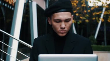 Dışarıda merdivenlerde oturan yakışıklı genç işadamı laptopuyla çalışıyor.. 