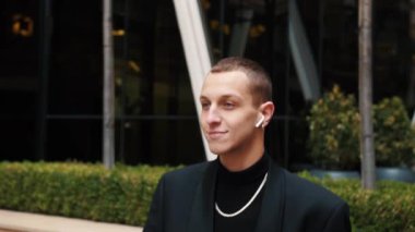 Kulaklıklı mutlu beyaz adam dışarıda dans edip şarkı söyleyen ve akıllı telefon tutarak sokakta eğlenen müzik dinliyor. Gençlik kültürü ve cihazları kavramı.