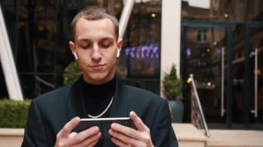 Cep telefonu kullanan yakışıklı, beyaz tenli bir iş adamı. Ofis Bölgesi 'nde yürürken mesaj atan genç bir adam. İş için. Sosyal ağ. - İnsanlar. Uygulamalar.