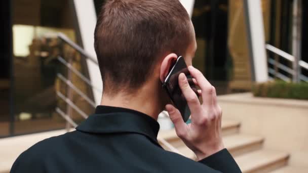 Backview Hombre llamar al teléfono al aire libre. startupper caucásica hablando de teléfono móvil fuera. hombre de negocios hablando en teléfono inteligente en la calle — Vídeos de Stock