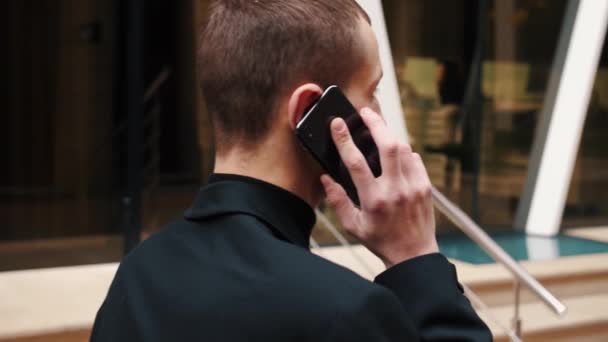 Backview Man bellen telefoon buiten. Kaukasische startupper praat mobiele telefoon buiten. zakenman aan het praten op smartphone op straat — Stockvideo