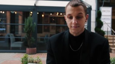 Kafkasyalı genç işadamı ofis dışındaki işi için bilgisayar kullanıyor. Cafe, şehir sokağı.