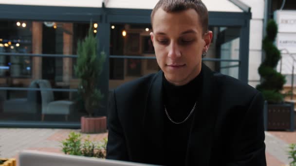 Jeune homme d'affaires caucasien utilisant ordinateur portable pour son travail à l'extérieur du bureau. Café, rue urbaine — Video