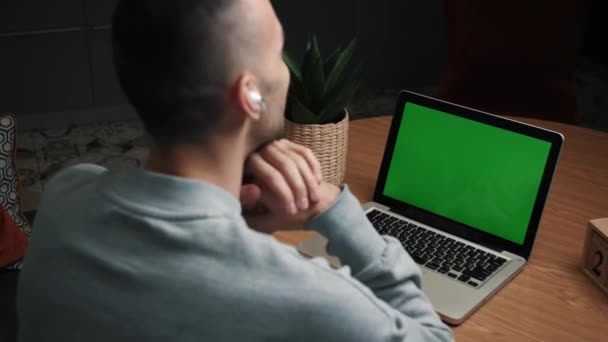 Κοντινό πλάνο φωτογραφία πίσω όψη του νεαρού άνδρα έχοντας μια βιντεοκλήση στο φορητό υπολογιστή με πράσινη οθόνη στο σπίτι — Αρχείο Βίντεο