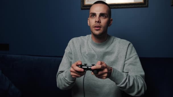 Opgewonden grappige jonge Kaukasische man gamers met controllers spelen video game. Overhappy man winnende video game plezier hebben op de bank vieren overwinning thuis. — Stockvideo