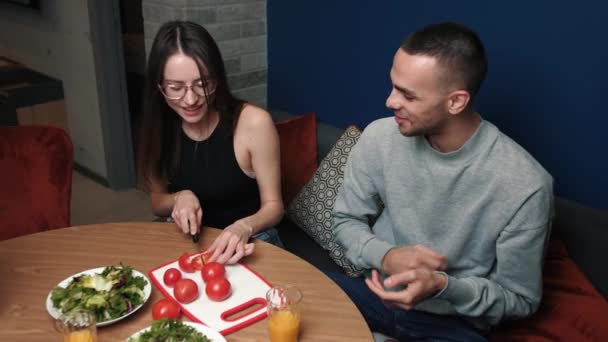 若い幸せなカップルの料理一緒に夕食を準備野菜を切り、自宅で話す — ストック動画