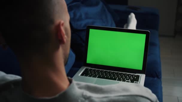 Man med laptop grön skärm avkopplande en på soffan. — Stockvideo