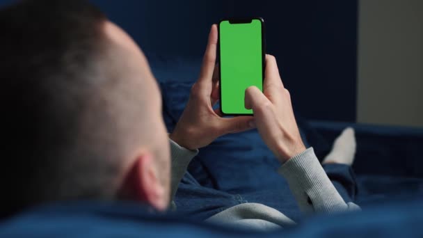 Man liggend op de bank met behulp van smartphone met chroma toets groen scherm, scrollen verschillende gebaren zoals vegen en scrollen - internet, communicatie concept close-up 4k template — Stockvideo